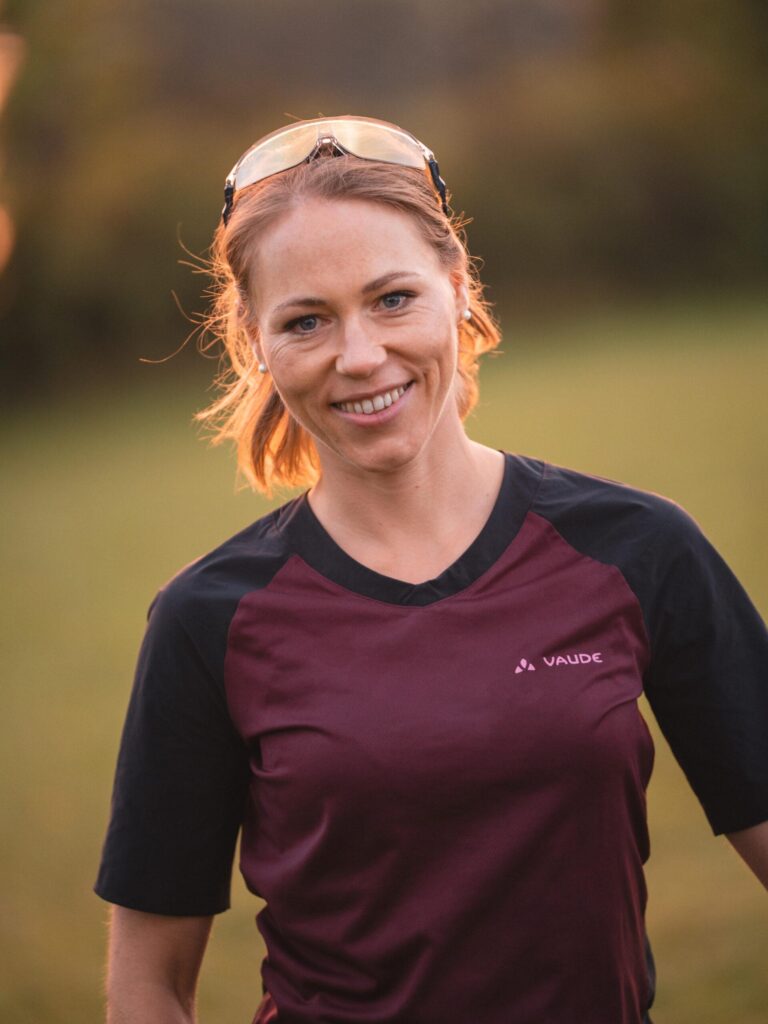 Porträt von Kerstin, einer freundlichen Trainerin, bei Sonnenlicht im Freien.